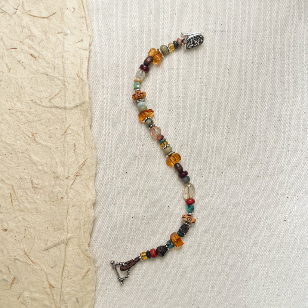 Woman wearing colorful mixed bead bracelet on wrist, adjustable hippie style wristband.