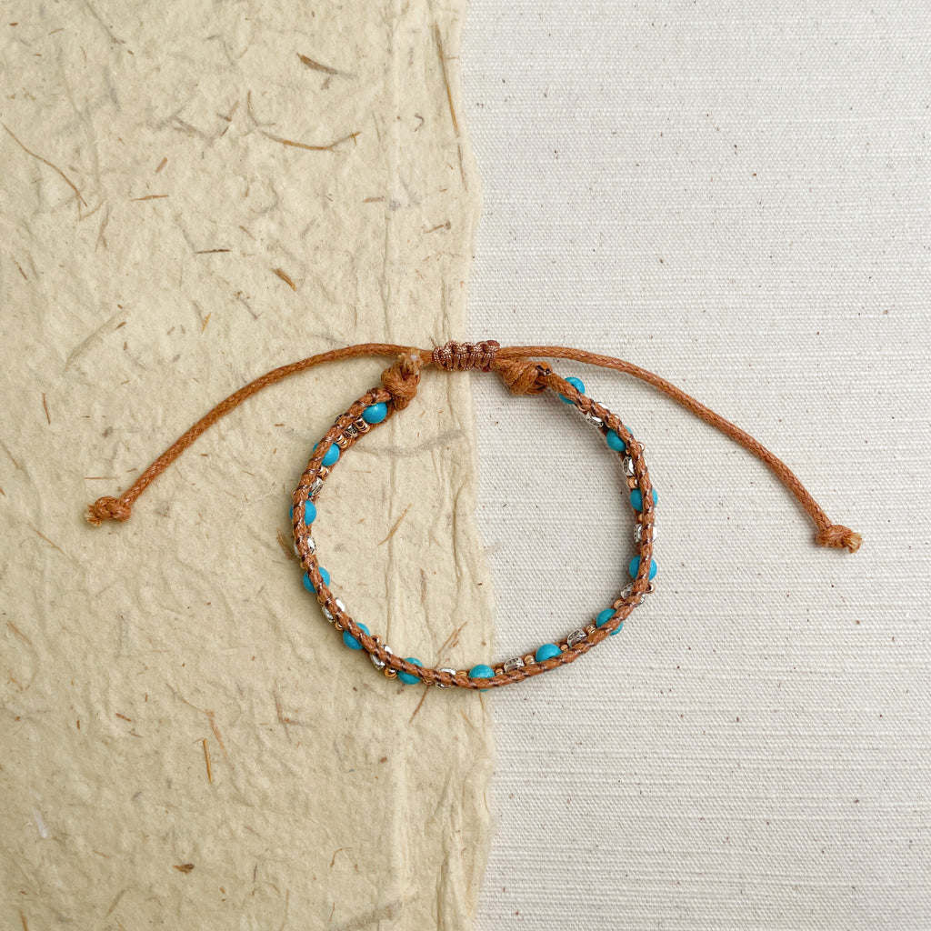 Adjustable turquoise wrap bracelet on wrist, rustic boho style jewelry.