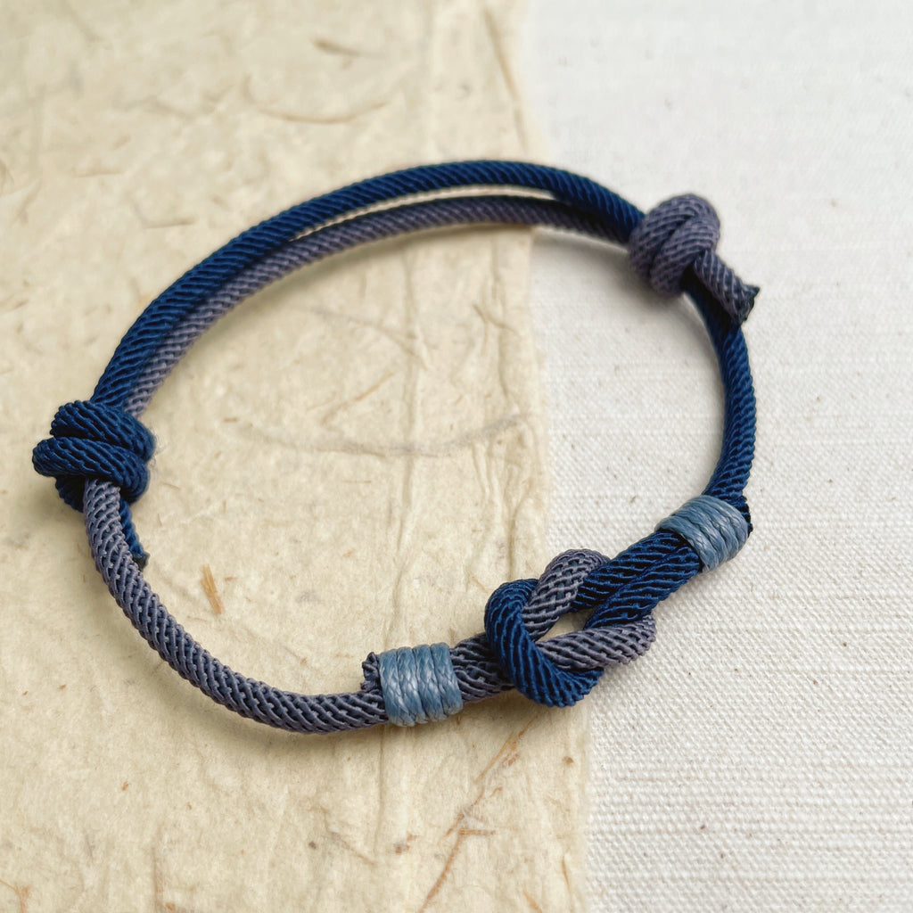 Unisex woven string bracelet in blue and gray, adjustable handmade jewelry.