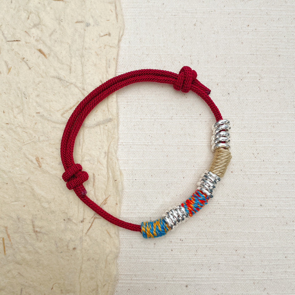 Handmade red braided bracelet with alloy accents, symbol of strength and luck.