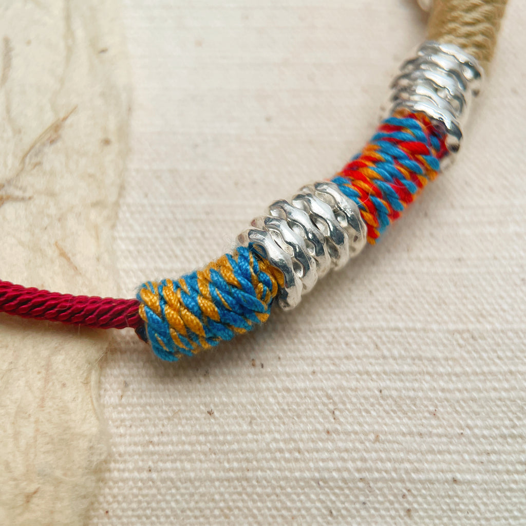 Adjustable red cord bracelet with colorful thread details, vibrant energy accessory
