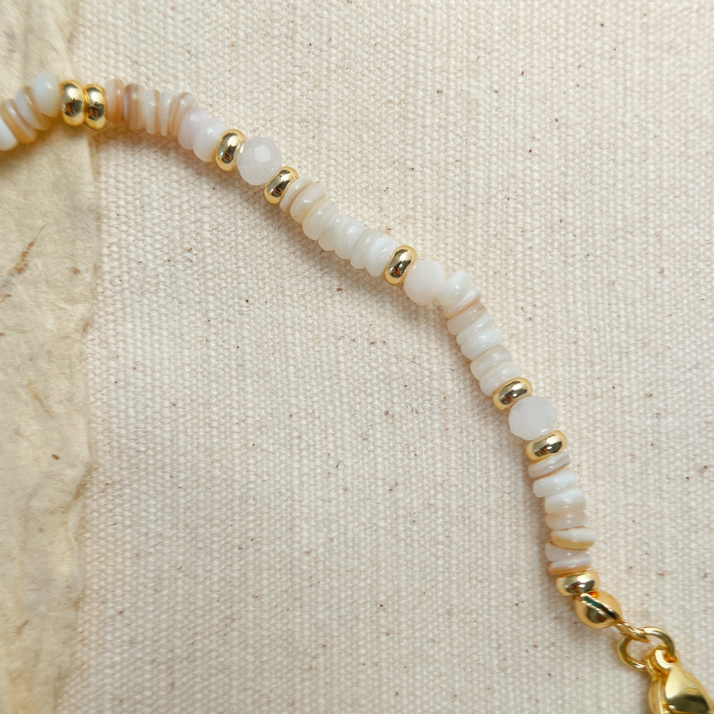 Beaded bracelet with gold accents on a beige fabric background