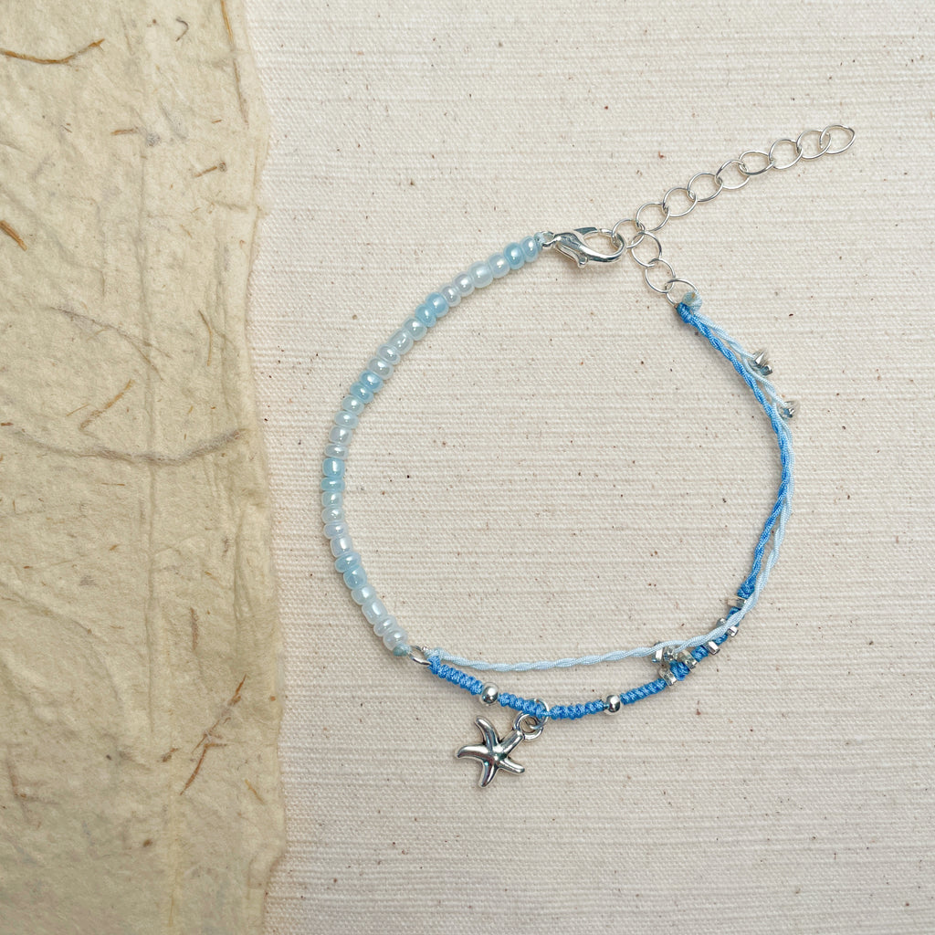 Handmade ocean blue beaded bracelet with starfish charm, coastal boho jewelry.