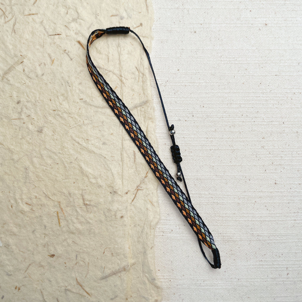 Black woven friendship bracelet on wrist, adjustable unisex boho jewelry.