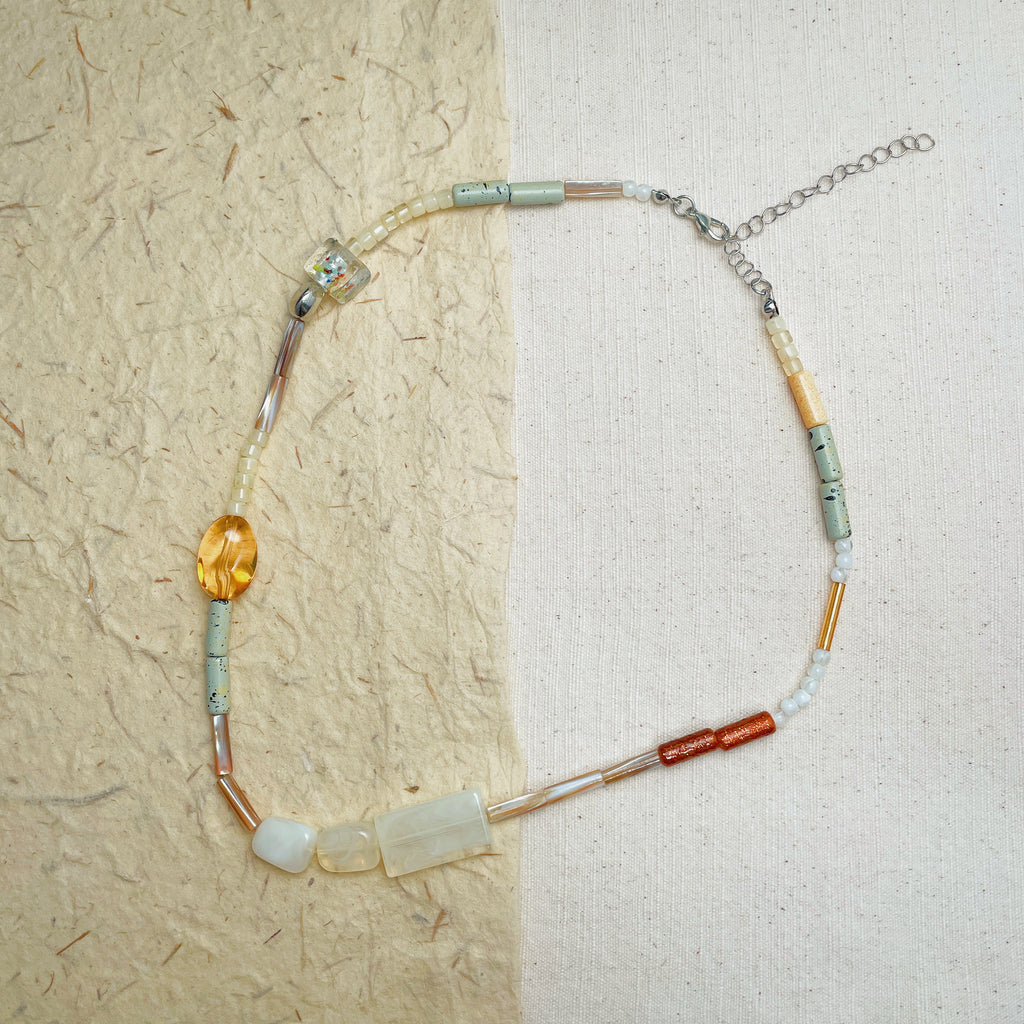 Vintage-inspired beaded necklace with warm brown, cream, and green tones, artistic eclectic jewelry