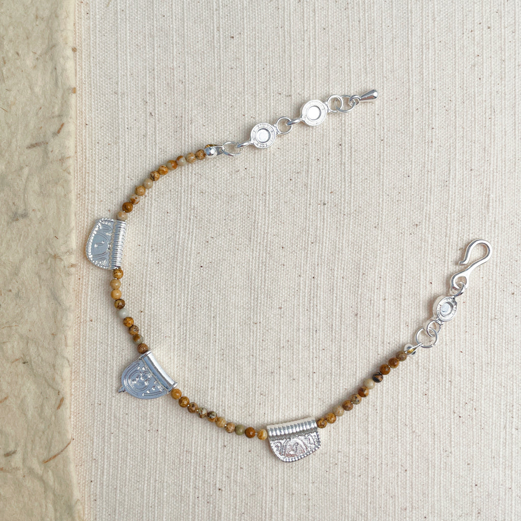 Adjustable brown stone charm bracelet on wrist, boho grounding energy jewelry.