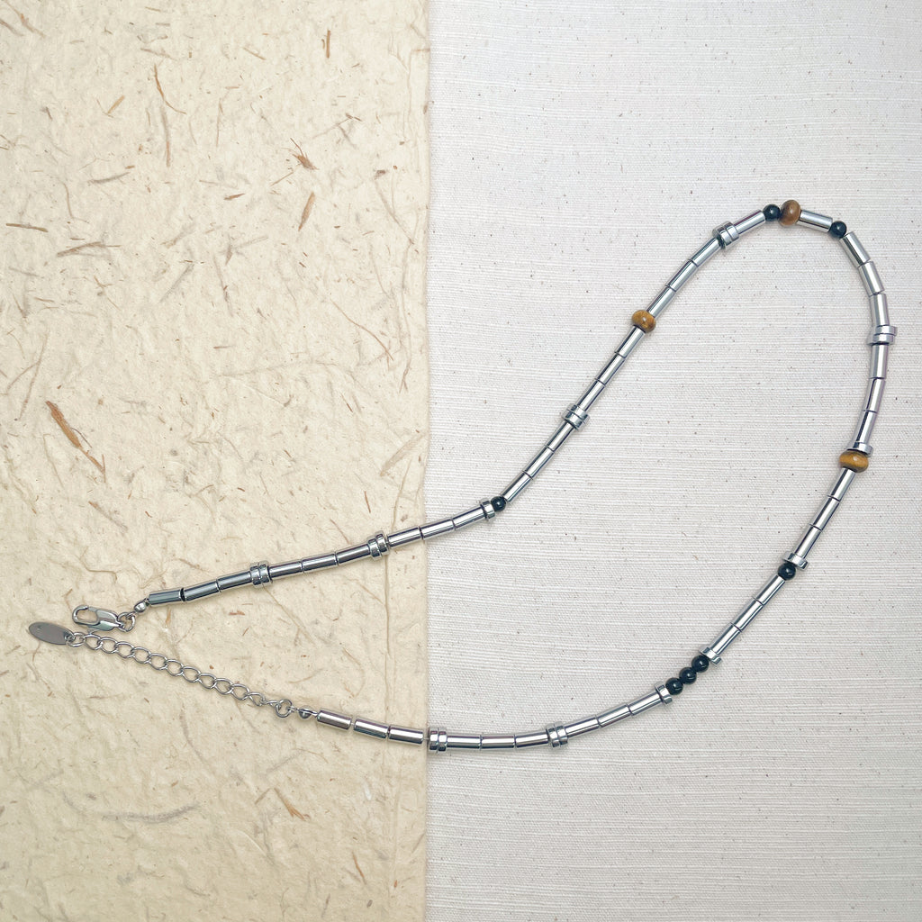 Minimalist tube bead necklace featuring silver-tone beads mixed with brown and black stones.